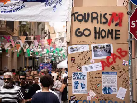 «Tourists go home» beziehungsweise «Tourism go home» steht an einer Wand in Barcelona (August 2024). - Foto: Marc Asensio Clupes/ZUMA Press Wire/dpa