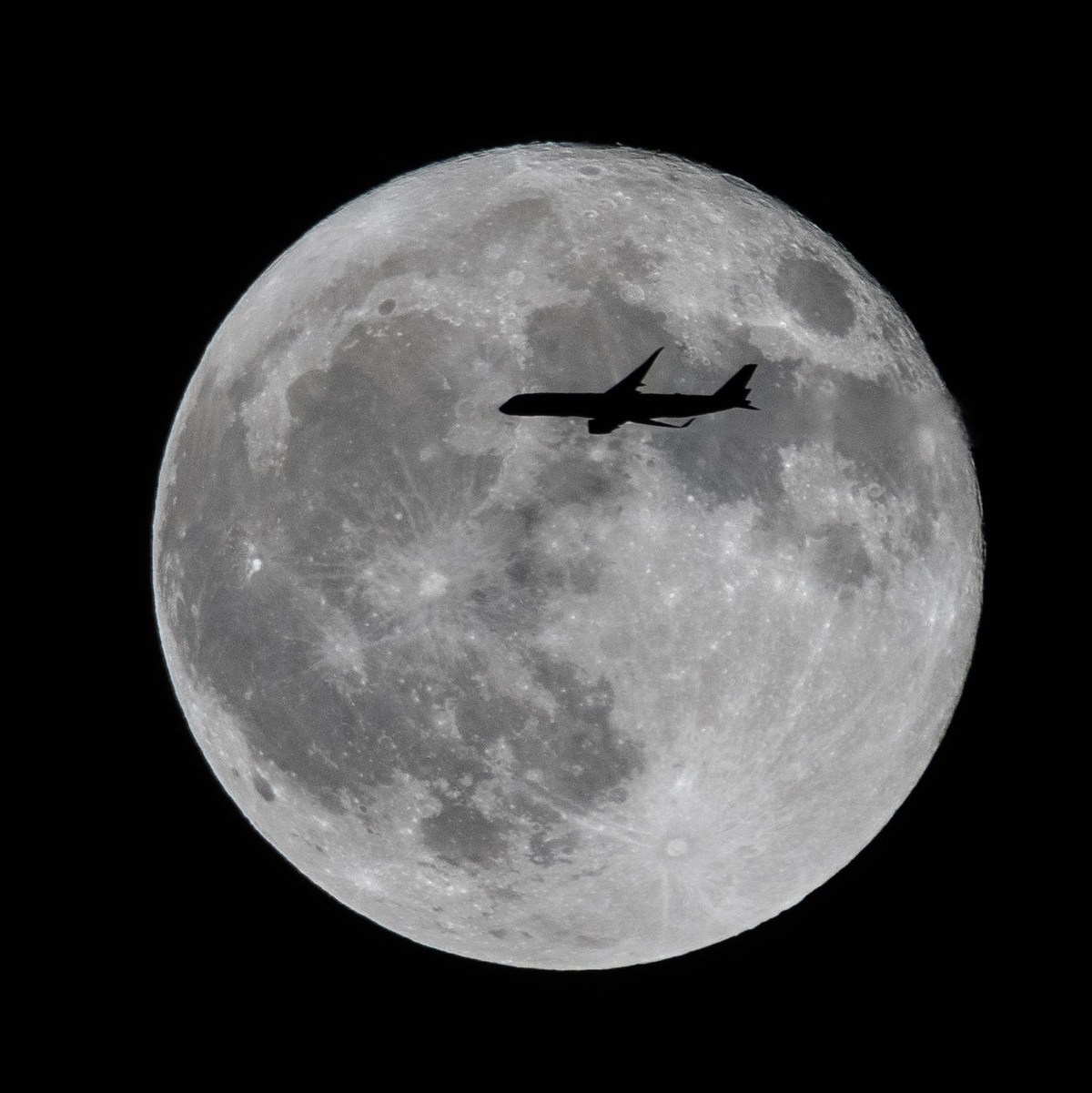 Ein Flugzeug fliegt an einem großen Vollmond vorbei. - Foto: Ringo Chiu/SOPA Images/ZUMA Press Wire/dpa