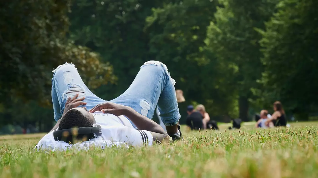 Musik hören im Park auf der Wiese - mehr Sommer geht kaum. Was wird der Sommerhit '24? (Illustration) - Bild: Annette Riedl/dpa