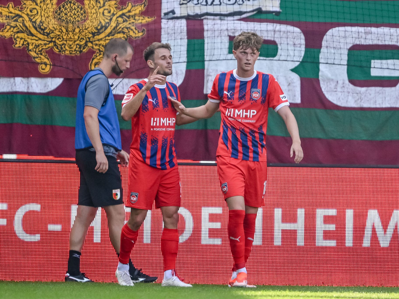 In dieser Szene berührt Augsburgs Schlotterbeck den Ball mit dem linken Arm. Die Folge: Handelfmeter für Heidenheim. - Foto: Harry Langer/dpa
