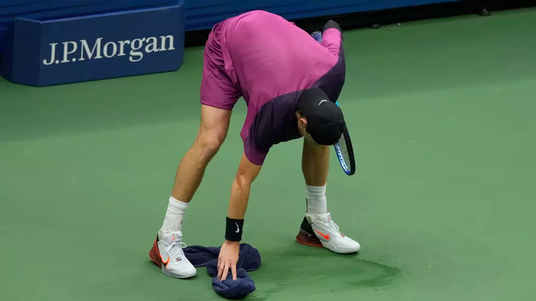 Jack Draper macht mit einem Handtuch den Platz sauber. - Bild: Seth Wenig/AP/dpa