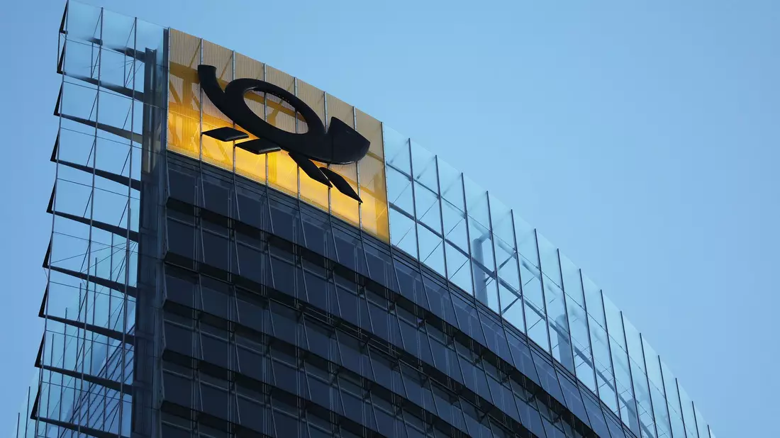 Das Logo der Deutschen Post leuchtet am Post-Tower, dem Unternehmenssitz des Post-Konzerns DHL. - Bild: Oliver Berg/dpa
