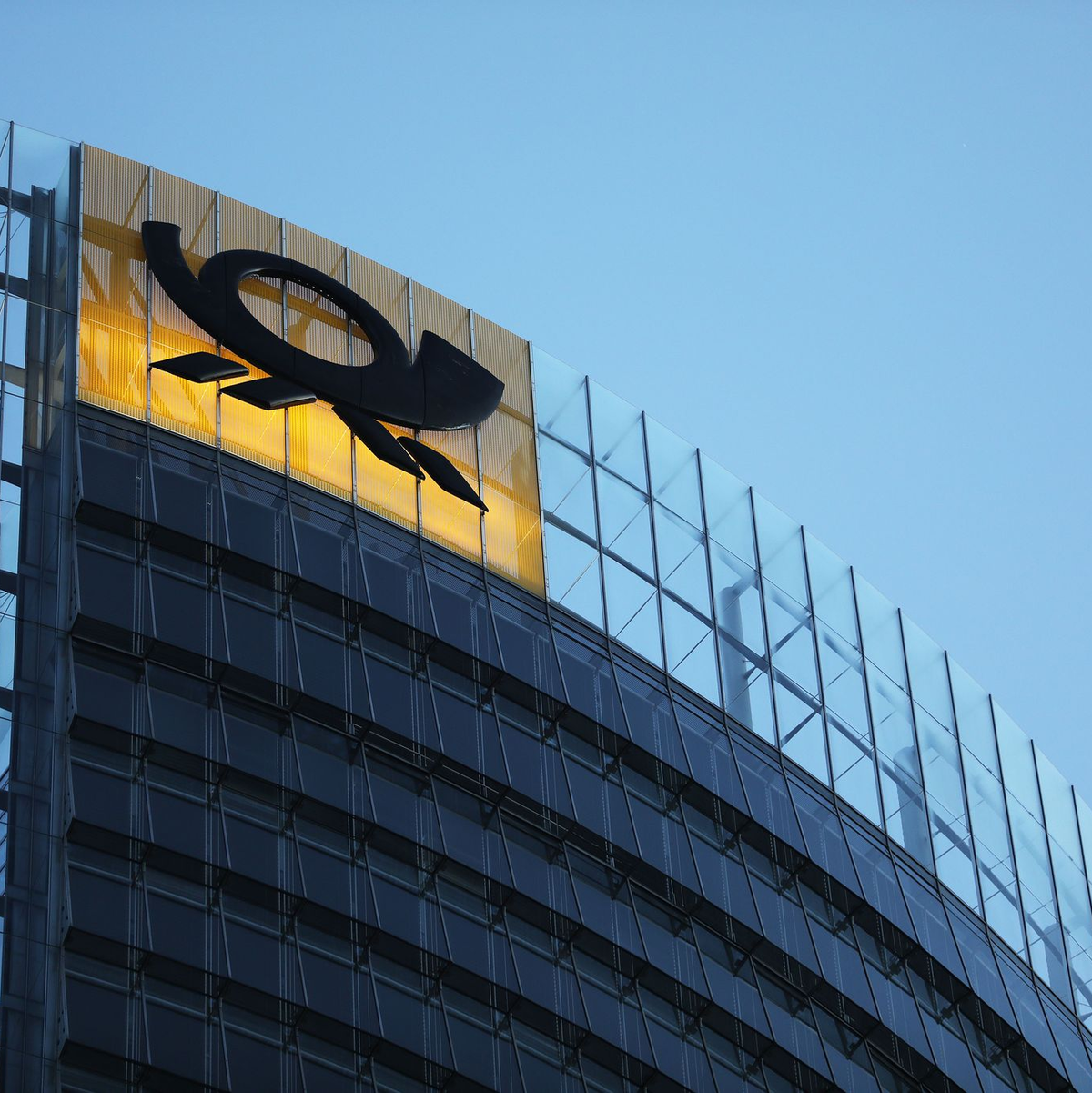 Das Logo der Deutschen Post leuchtet am Post-Tower, dem Unternehmenssitz des Post-Konzerns DHL. - Foto: Oliver Berg/dpa