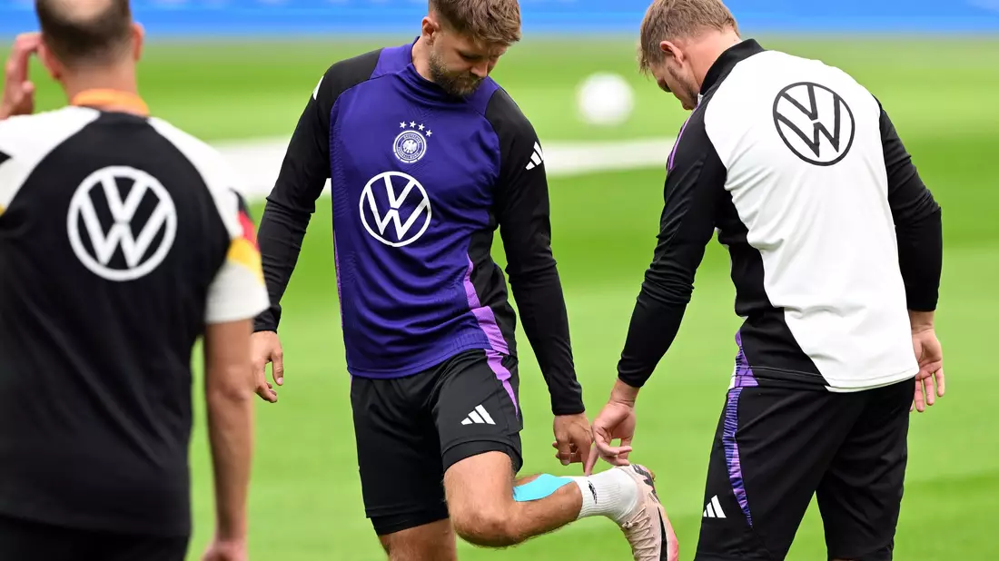 Niclas Füllkrug (M) nach seinem vergeblichen Härtetest beim Abschlusstraining im Gespräch mit Bundestrainer Julian Nagelsmann (r).  - Bild: Federico Gambarini/dpa