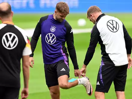 Niclas Füllkrug (M) nach seinem vergeblichen Härtetest beim Abschlusstraining im Gespräch mit Bundestrainer Julian Nagelsmann (r).  - Foto: Federico Gambarini/dpa