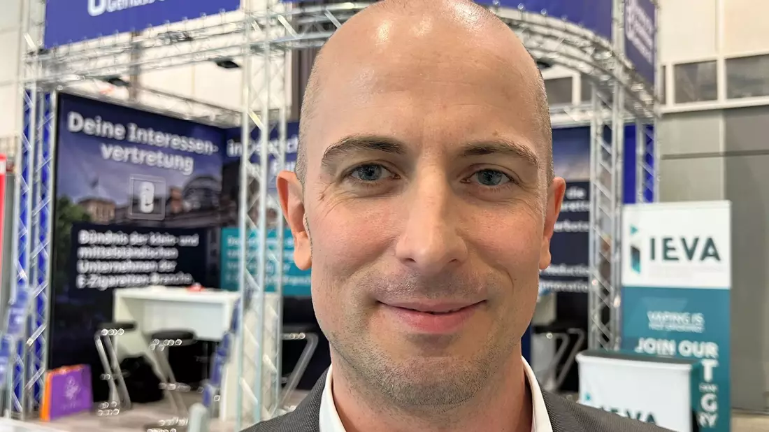 Dustin Dahlmann, Vorsitzender des E-Zigaretten-Verbandes «Bündnis für Tabakfreien Genuss» (BfTG), steht bei der Messe Intertabac 2023 vor einem Stand seiner Organisation. - Bild: Wolf von Dewitz/dpa