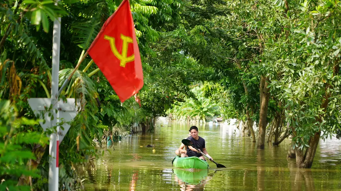 Ein Mann paddelt in der Nähe von Hanoi durch das Hochwasser. - Bild: Hau Dinh/AP/dpa
