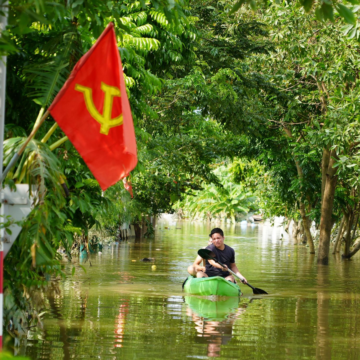 Ein Mann paddelt in der Nähe von Hanoi durch das Hochwasser. - Foto: Hau Dinh/AP/dpa