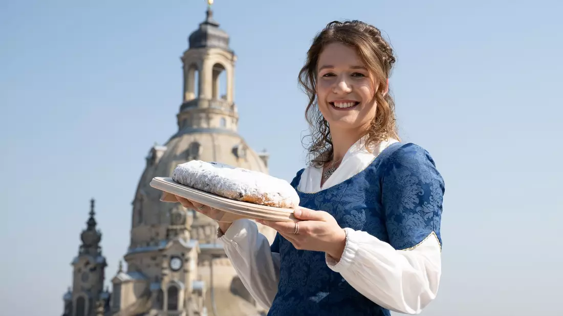Das 30. Dresdner Stollenmädchen mit einem der berühmten Striezel vor der Frauenkirche - Bild: Sebastian Kahnert/dpa