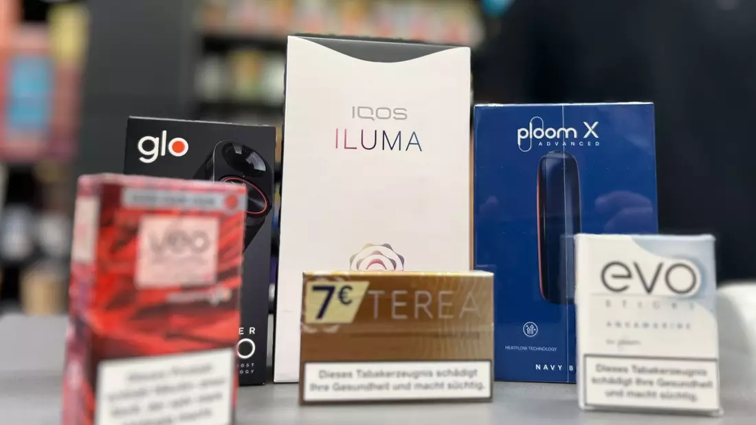 Die Tabakerhitzer-Elektrogeräte der Marken Glo von British American Tobacco (BAT), Iqos von Philip Morris und Ploom von Japan Tobacco International (JTI) mit den dazugehörigen Tabakstick-Marken liegen auf der Verkaufstheke eines Geschäfts. - Bild: Wolf von Dewitz/dpa