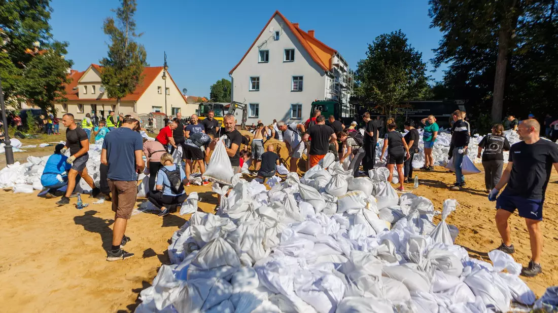 Menschen arbeiten in Polen an der Verstärkung der Deiche. - Bild: Krzysztof Zatycki/ZUMA Press Wire/dpa