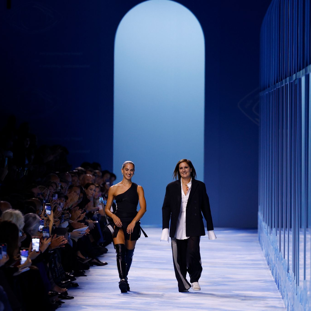 Designerin Maria Grazia Chiuri (r) geht neben einem Model. - Foto: Vianney Le Caer/Invision/AP/dpa