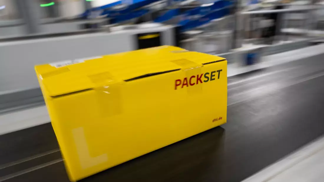 Ein Paket rollt über das Laufband eines DHL-Paketzentrums. - Bild: Christophe Gateau/dpa