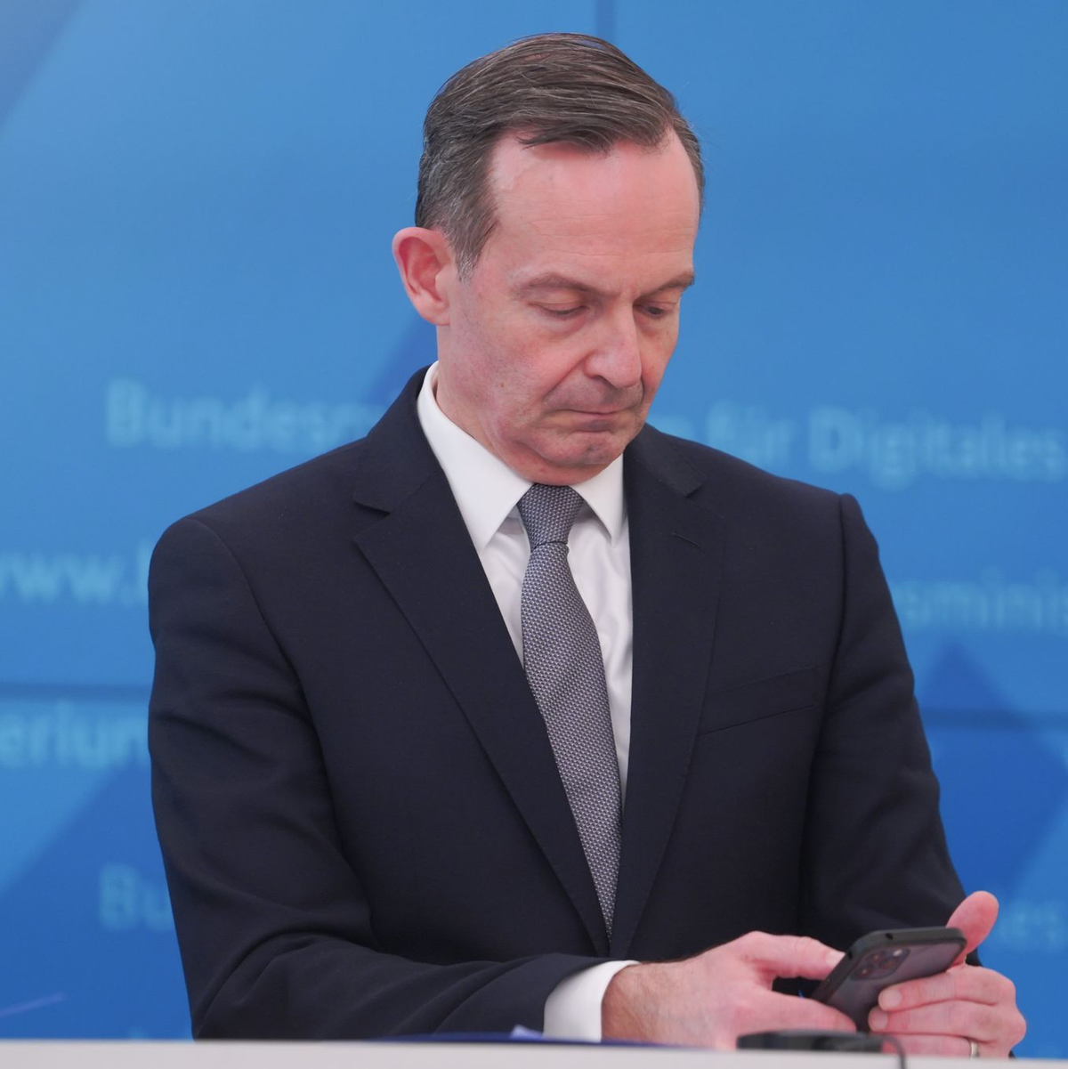 Bundesverkehrsminister Volker Wissing (FDP) blickt bei einer Pressekonferenz im März 2022 auf sein Smartphone. - Foto: Joerg Carstensen/dpa