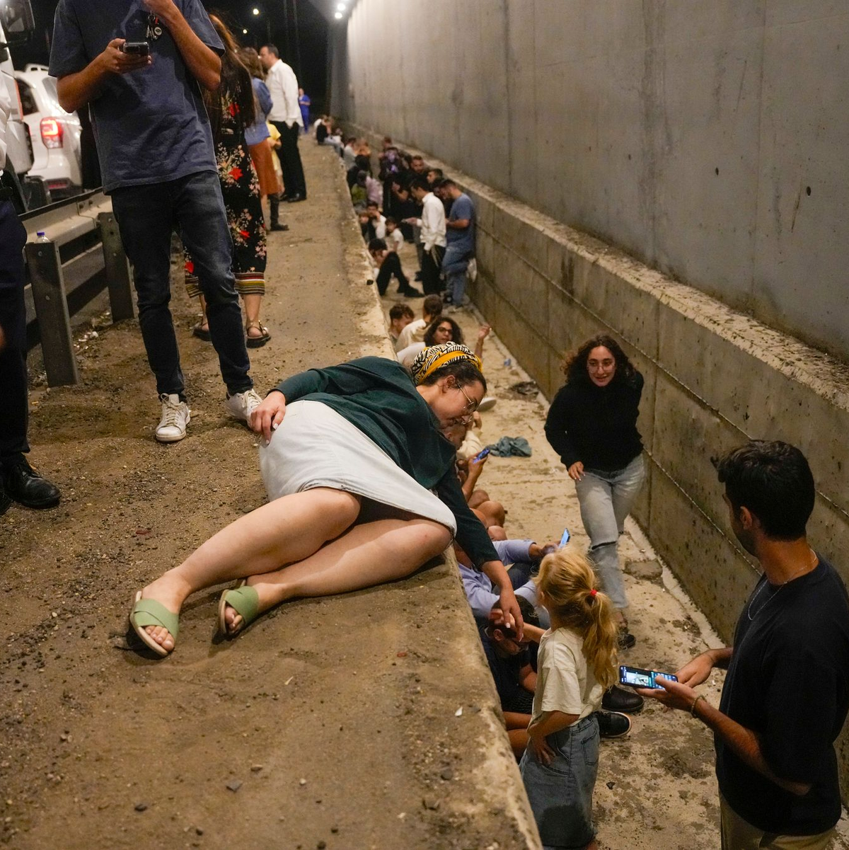 Menschen gehen am Straßenrand in Deckung, während eine Sirene auf einer Autobahn vor ankommenden Raketen warnt. - Foto: Ohad Zwigenberg/AP/dpa