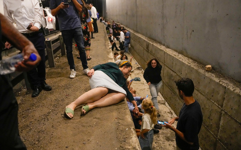 Menschen gehen am Straßenrand in Deckung, während eine Sirene auf einer Autobahn vor ankommenden Raketen warnt. - Foto: Ohad Zwigenberg/AP/dpa