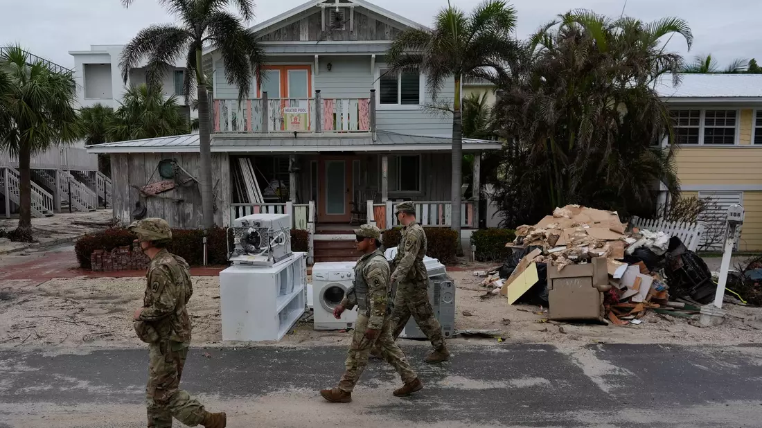 Nationalgardisten suchen nach verbliebenen Bewohnern im fast menschenleeren Bradenton Beach. Den Anwohnern blieb nach Hurrikan «Helene» keine Zeit, die Schuttberge zu beseitigen.  - Bild: Rebecca Blackwell/AP/dpa