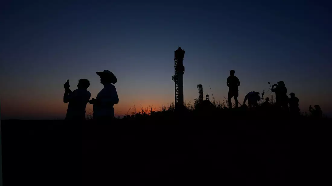 Menschen fotografieren den Sonnenuntergang hinter der Rakete Starship von SpaceX. - Bild: Eric Gay/AP