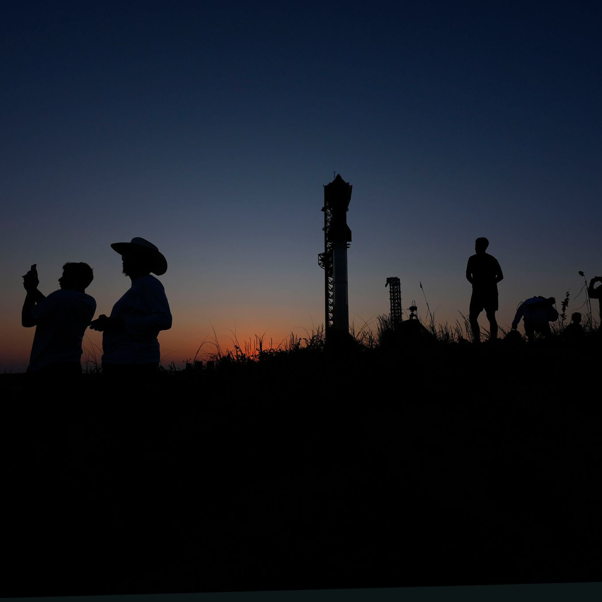 Menschen fotografieren den Sonnenuntergang hinter der Rakete Starship von SpaceX. - Foto: Eric Gay/AP
