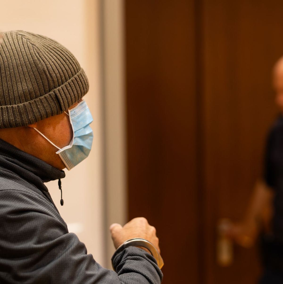 Ein Justizbeamter nimmt dem Angeklagten (links) im Gerichtssaal die Handschellen ab, während dessen Verteidiger daneben steht. - Foto: Philipp von Ditfurth/dpa