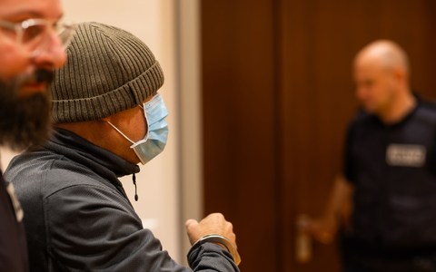 Ein Justizbeamter nimmt dem Angeklagten (links) im Gerichtssaal die Handschellen ab, während dessen Verteidiger daneben steht. - Foto: Philipp von Ditfurth/dpa