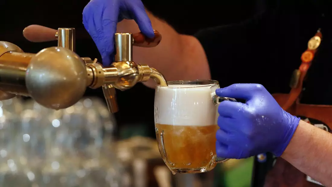 Ein Barkeeper zapft ein Bier auf einer Restaurant-Terrasse. (Symbolbild) - Bild: Petr David Josek/AP/dpa