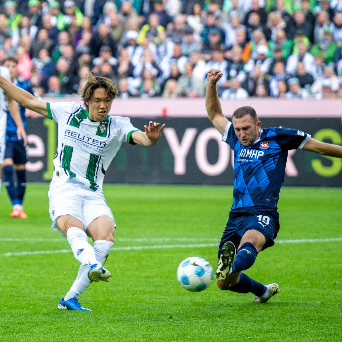 Der Mönchengladbacher Ko Itakura (l) trifft in dieser Szene zum 1:1, Heidenheims Jonas Föhrenbach grätscht zu spät dazwischen. - Foto: David Inderlied/dpa