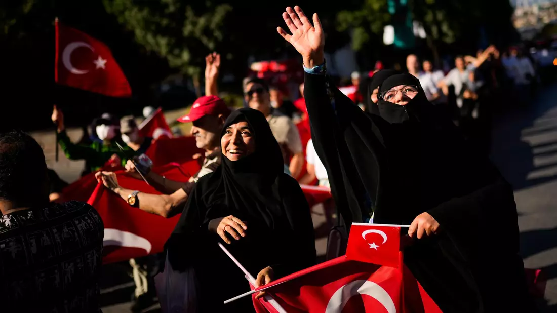 Menschen halten türkische Flaggen hoch, während sie sich zu Ehren der Opfer des gescheiterten Putschversuchs vom 15. Juli 2016 versammelten. (Archivbild) - Bild: Francisco Seco/AP/dpa