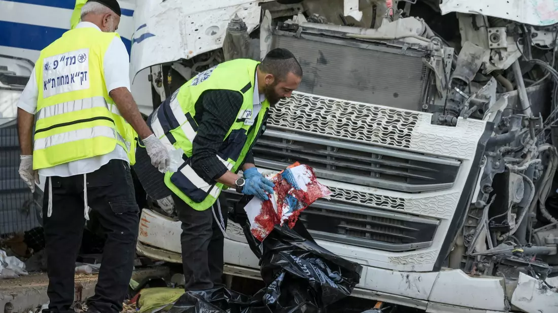 Mitglieder des Rettungs- und Bergungsteams Zaka arbeiten an der Stelle, an der ein Lkw-Fahrer eine Bushaltestelle gerammt und dabei Dutzende von Menschen verletzt hat. - Bild: Oded Balilty/AP