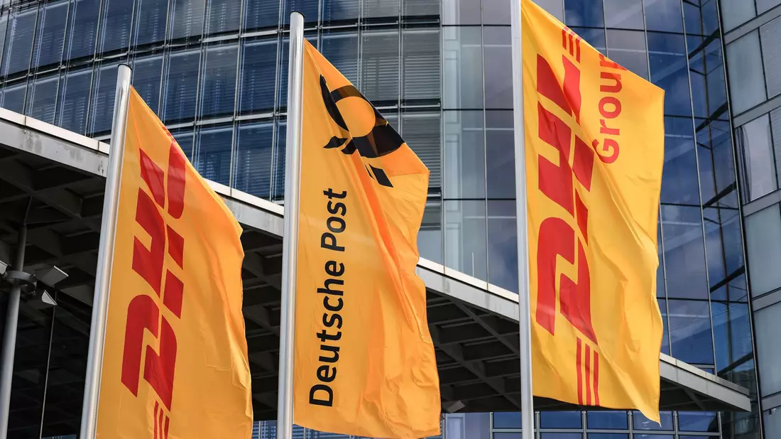 Fahnen wehen vor der Zentrale der DHL Group, die sich im Briefgeschäft Deutsche Post nennt.  - Bild: Oliver Berg/dpa