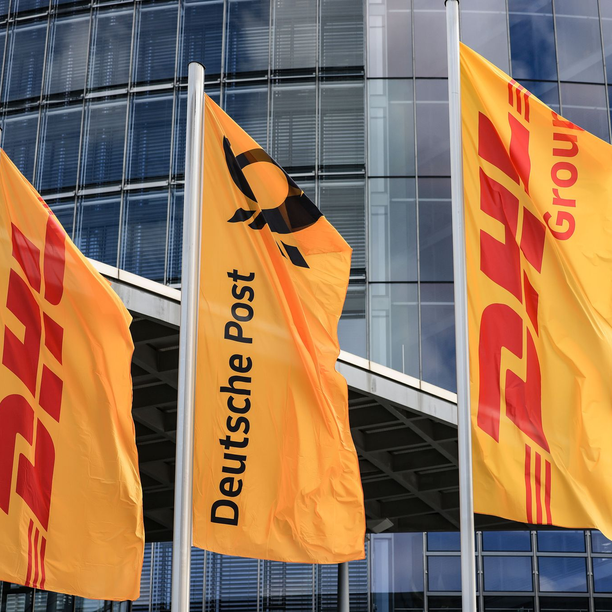 Fahnen wehen vor der Zentrale der DHL Group, die sich im Briefgeschäft Deutsche Post nennt.  - Foto: Oliver Berg/dpa