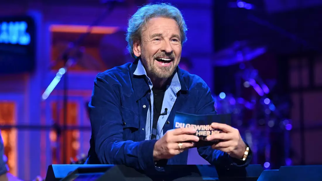 In Schlaghosen kommt Thomas Gottschalk durch eine Tür, über der NWSDWH steht. Er ist Gast in der RTL+-Streaming-Show «Du gewinnst hier nicht die Million bei Stefan Raab» - Bild: Julia Feldhagen/RTL/Raab Entertainment /dpa