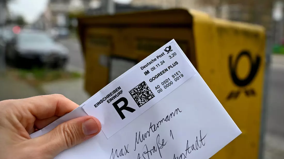 Ein Mann hält ein sogenanntes Einwurf-Einschreiben vor einen Briefkasten (gestellte Szene). - Bild: Wolf von Dewitz/dpa