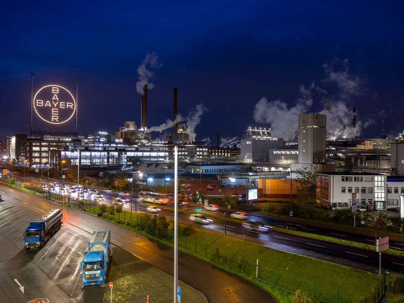 Das Bayer-Kreuz, das Logo des Unternehmens, leuchtet auf dem Werksgelände von Bayer in Leverkusen. - Foto: Thomas Banneyer/dpa