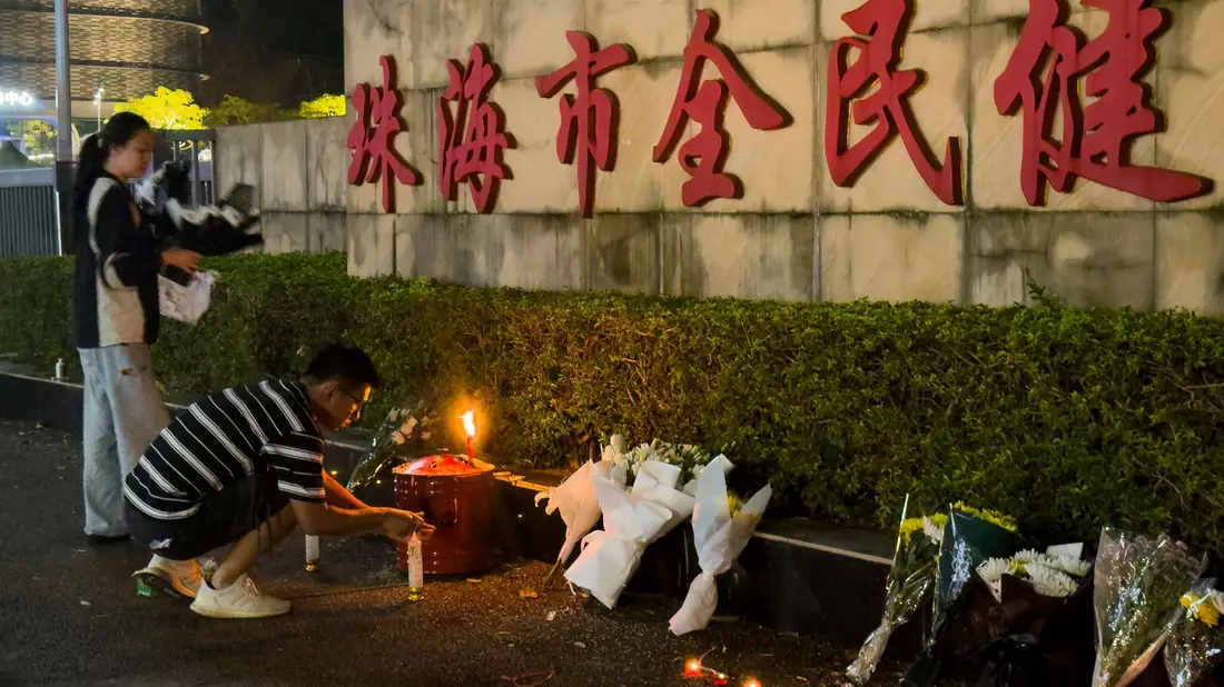 Menschen legen Blumen vor einem Sportzentrum nieder, wo ein Mann mit seinem Auto 35 Menschen tötete.  - Bild: Ng Han Guan/AP