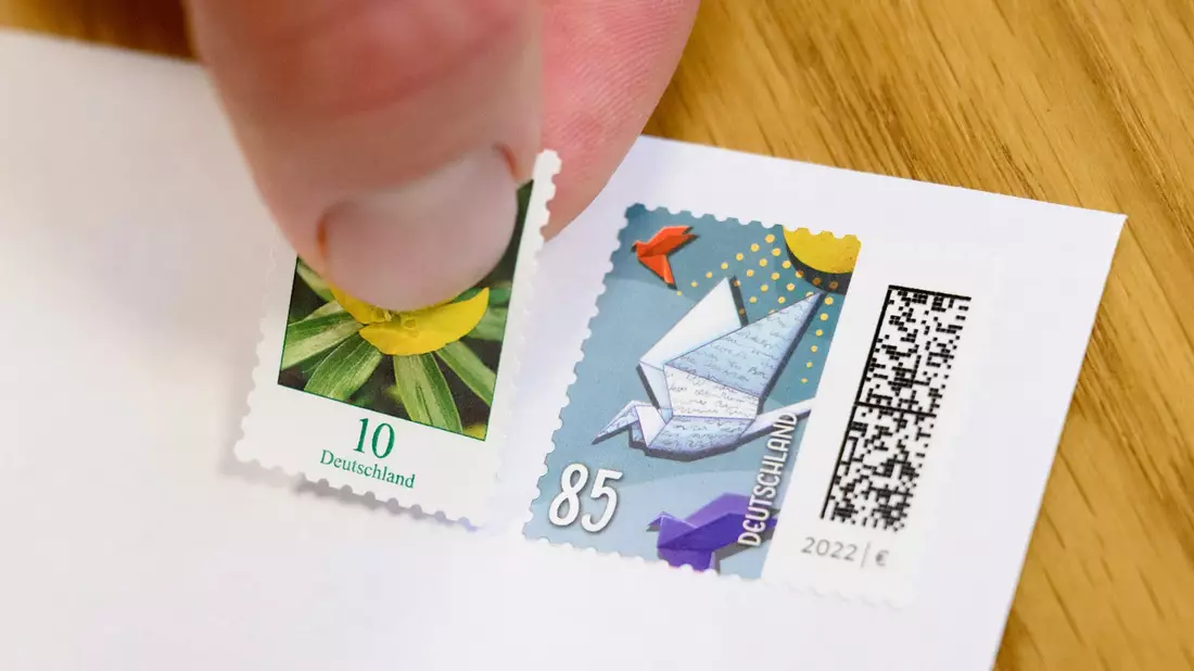 Eine 10-Cent-Briefmarke wird neben eine 85-Cent-Briefmarke geklebt (gestellte Szene).  - Bild: Julian Stratenschulte/dpa