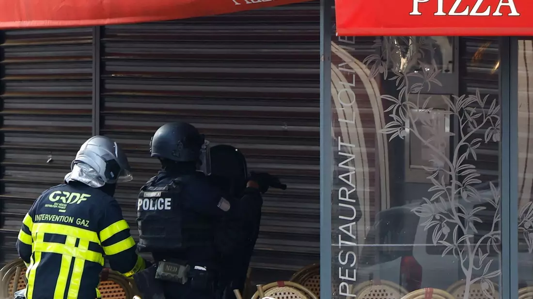 Polizisten stehen vor dem Restaurant in Issy-les-Moulineaux. - Bild: Ian Langsdon/AFP/dpa