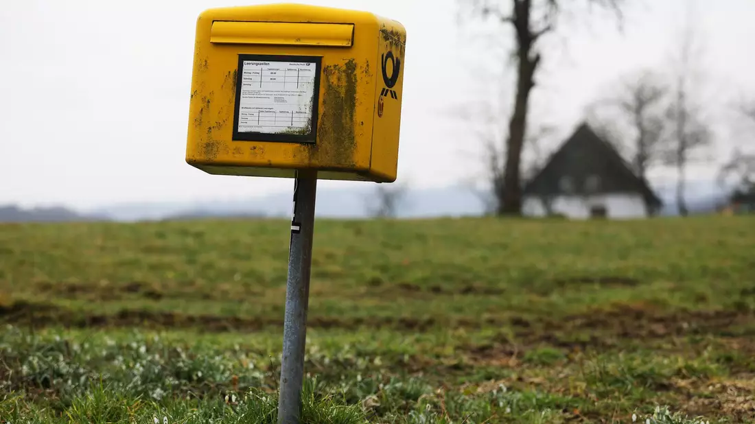 Ein Briefkasten der Deutschen Post steht auf einer Wiese am Rand einer Siedlung im Bergischen Land (NRW).  - Bild: Oliver Berg/dpa
