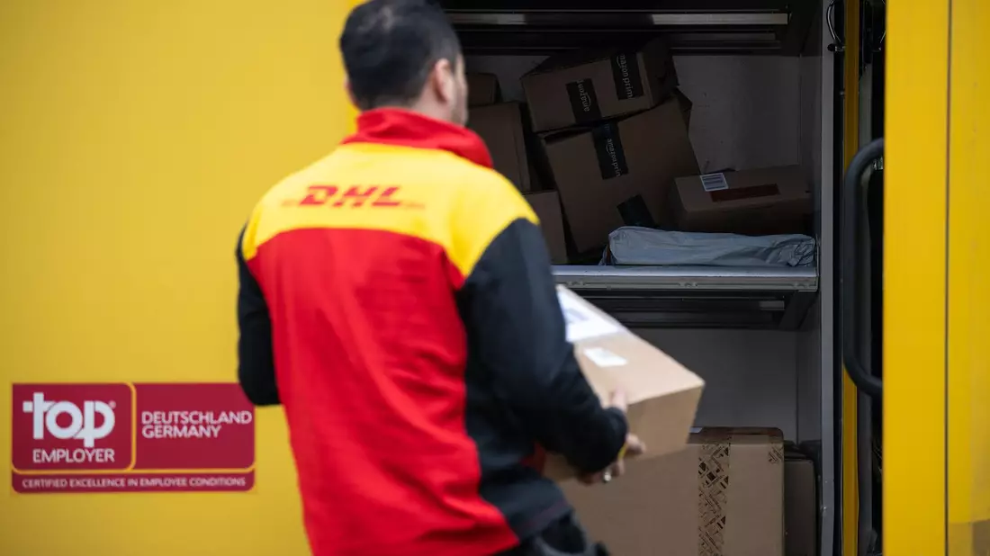 Ein Post-Mitarbeiter trägt ein Paket in einen Lieferwagen. - Bild: Hannes P. Albert/dpa