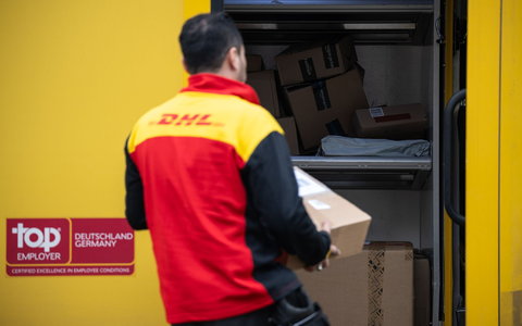 Ein Post-Mitarbeiter trägt ein Paket in einen Lieferwagen. - Foto: Hannes P. Albert/dpa
