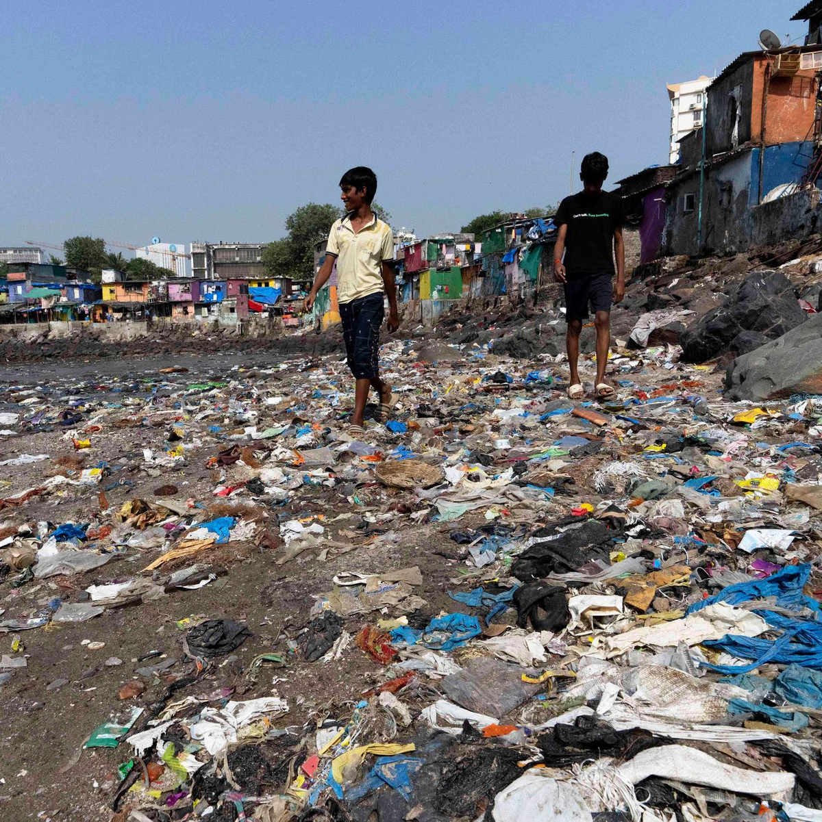 Menschen spazieren am Strand des Badhwar Park im indischen Mumbai an Plastikmüll vorbei. (Archivbild) - Foto: Rajanish Kakade/AP/dpa