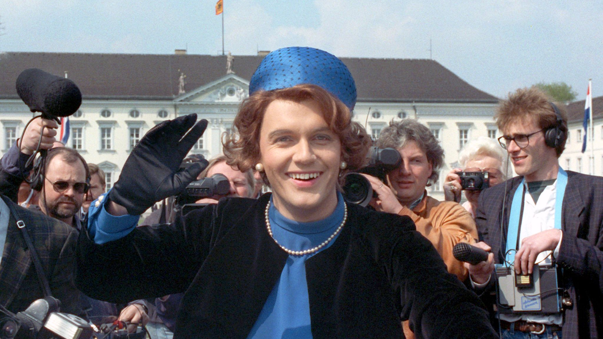 Verkleidet als Königin Beatrix winkt der deutsche Komiker und Showmaster Hape Kerkeling vor Schloss Bellevue für die Presse. (Archivfoto von 1991) - Foto: picture alliance / dpa