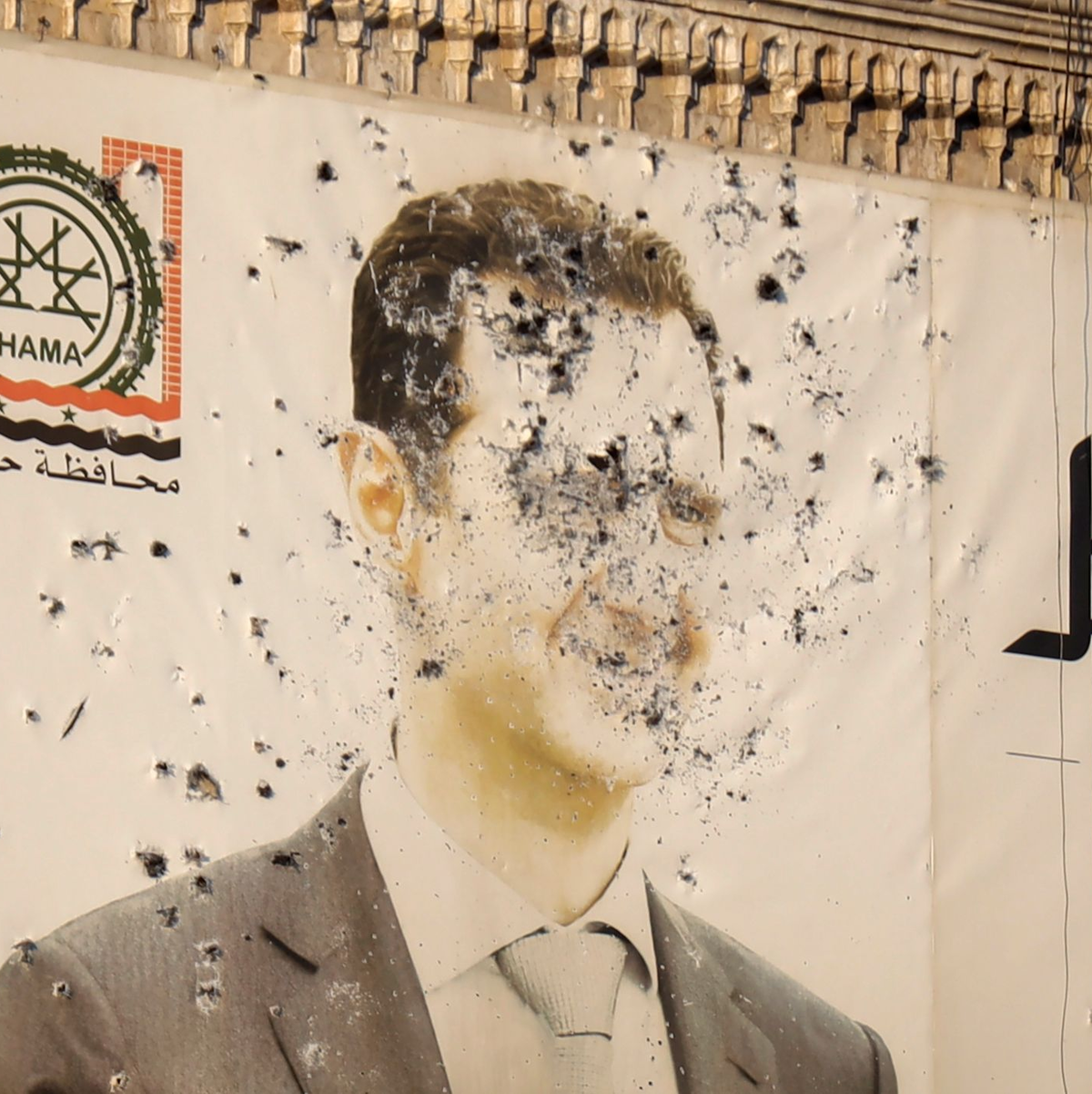 Ein Bild des syrischen Präsidenten Baschar al-Assad, durchlöchert von Kugeln, ist in der Stadt Hama zu sehen.  - Foto: Omar Albam/AP