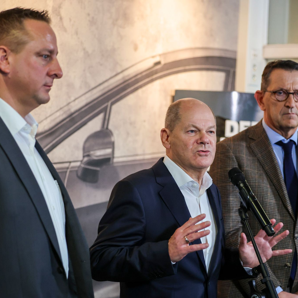 Betriebsratschef Benjamin Gruschka (l) neben Bundeskanzler Olaf Scholz (SPD) und Marcus Wassenberg (r), Geschäftsführer der Ford-Werke. - Foto: Christoph Reichwein/dpa