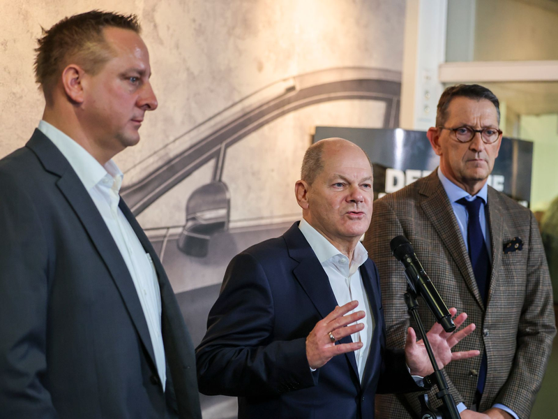 Betriebsratschef Benjamin Gruschka (l) neben Bundeskanzler Olaf Scholz (SPD) und Marcus Wassenberg (r), Geschäftsführer der Ford-Werke. - Foto: Christoph Reichwein/dpa