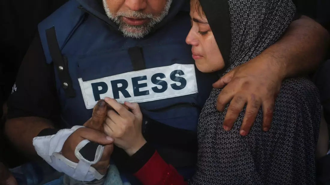 Der Al-Dschasira-Journalist Wael al-Dahdu hält die Hand seines Sohns Hamza, der ebenfalls für Al-Dschasira arbeitete und bei einem israelischen Luftangriff im Gazastreifen getötet wurde. - Bild: Hatem Ali/AP/dpa