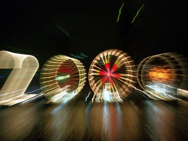 25 Jahre alt ist dieses «2000»-Foto: Ein Zoom-Effekt verfremdet eine große «2» und drei Riesenräder am Mainufer in Frankfurt in der Silvesternacht 1999/2000.  - Foto: Arne Dedert/dpa