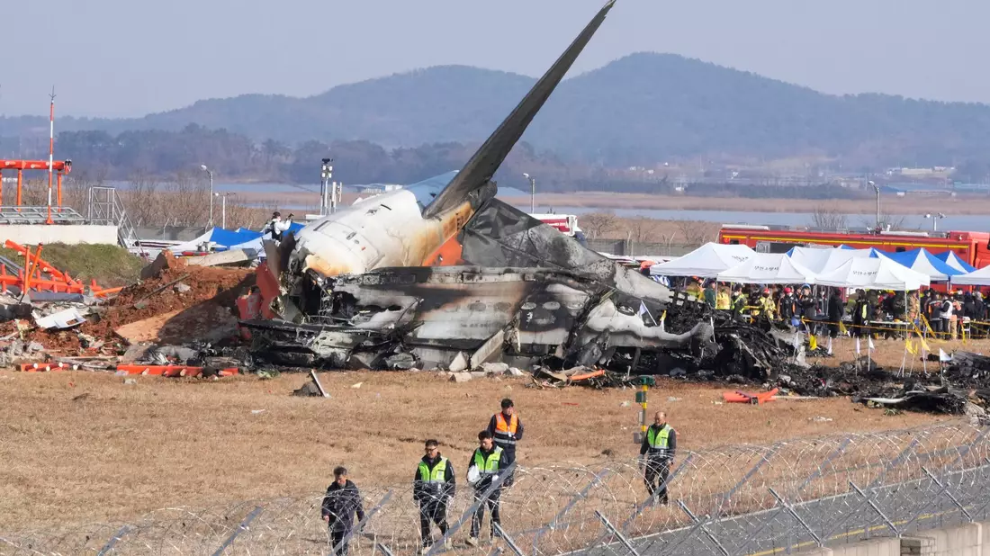 Feuerwehrleute und Rettungskräfte suchen am Wrack des verunglüclten Flugzeugs auf dem internationalen Flughafen von Muan nach Opfern.  - Bild: Ahn Young-joon/AP/dpa