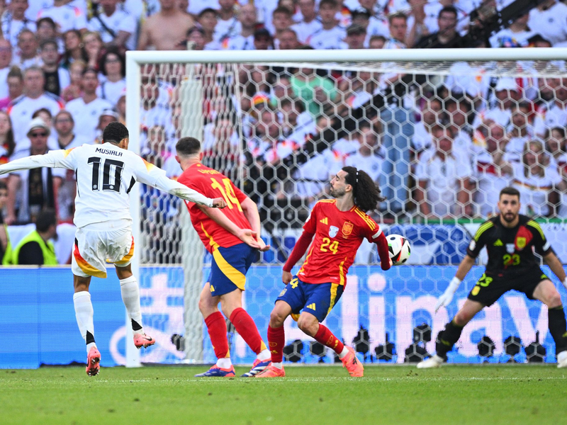 Jamal Musiala schießt - und Spaniens Marc Cucurella wehrt den Ball im EM-Viertelfinale mit dem abgespreizten Arm ab. - Foto: Tom Weller/dpa