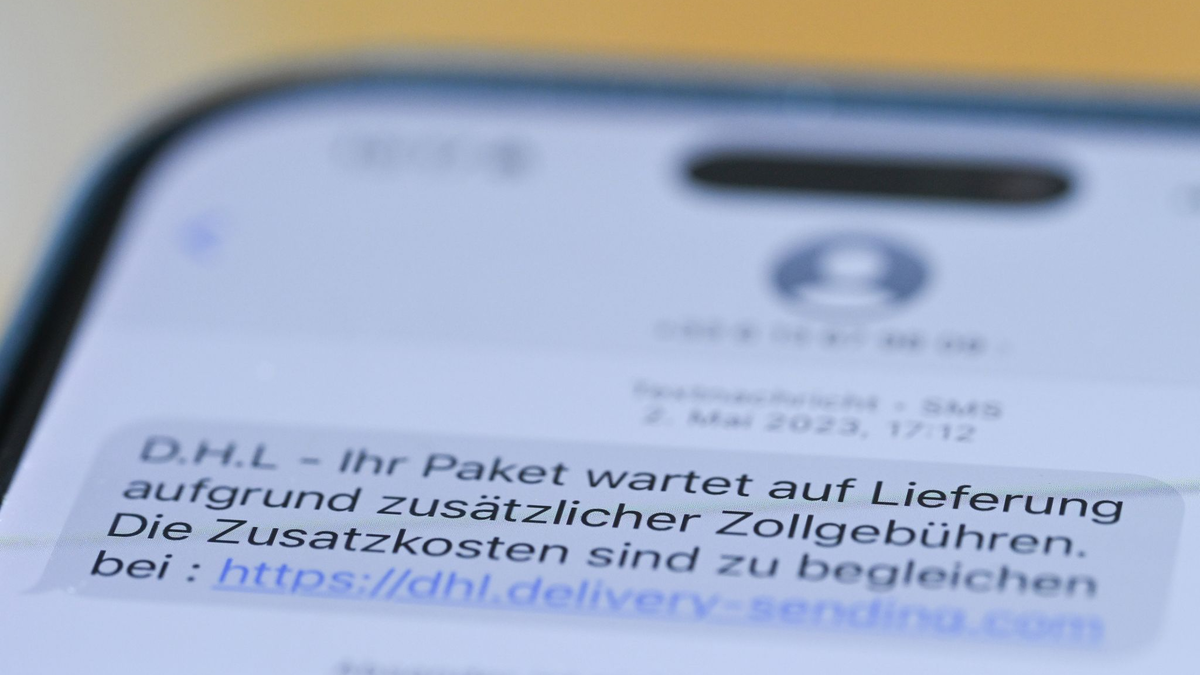 Auf einem Smartphone ist eine Betrugs-SMS zu lesen, in der Kriminelle ein Paket ankündigen und dafür Zollgebühren einfordern.  - Foto: Wolf von Dewitz/dpa